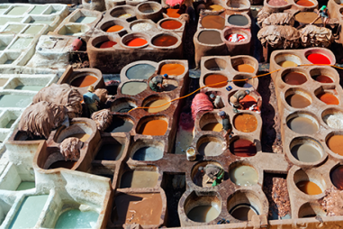 Photo of clay pots from above. The pots are filled with brightly coloured substances